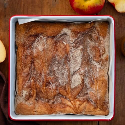Pan of Caramel Apple Cider Blondies on a wooden table with fresh apple.
