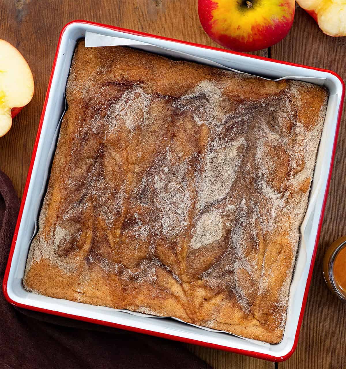 Pan of Caramel Apple Cider Blondies on a wooden table with fresh apple Pan of Caramel Apple Cider Blondies on a wooden table with fresh apple.