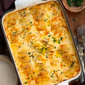 Cheesy Scalloped Potatoes for a Crowd in a large pan on a wooden table from overhead.