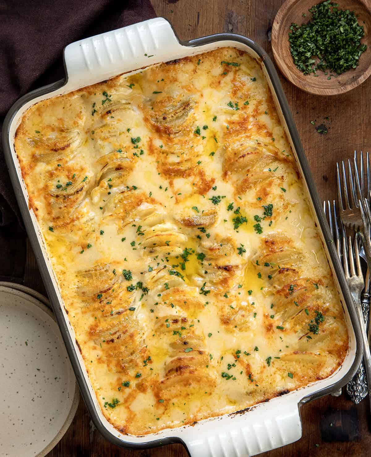 Cheesy Scalloped Potatoes for a Crowd in a large pan on a wooden table from overhead.