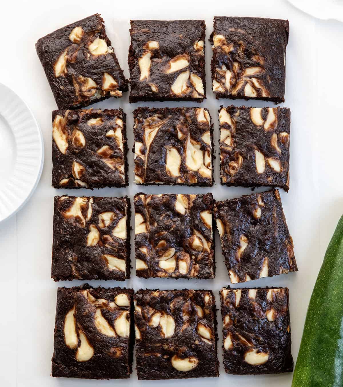 Cream Cheese Chocolate Zucchini Cake cut into squares on a white table from overhead.