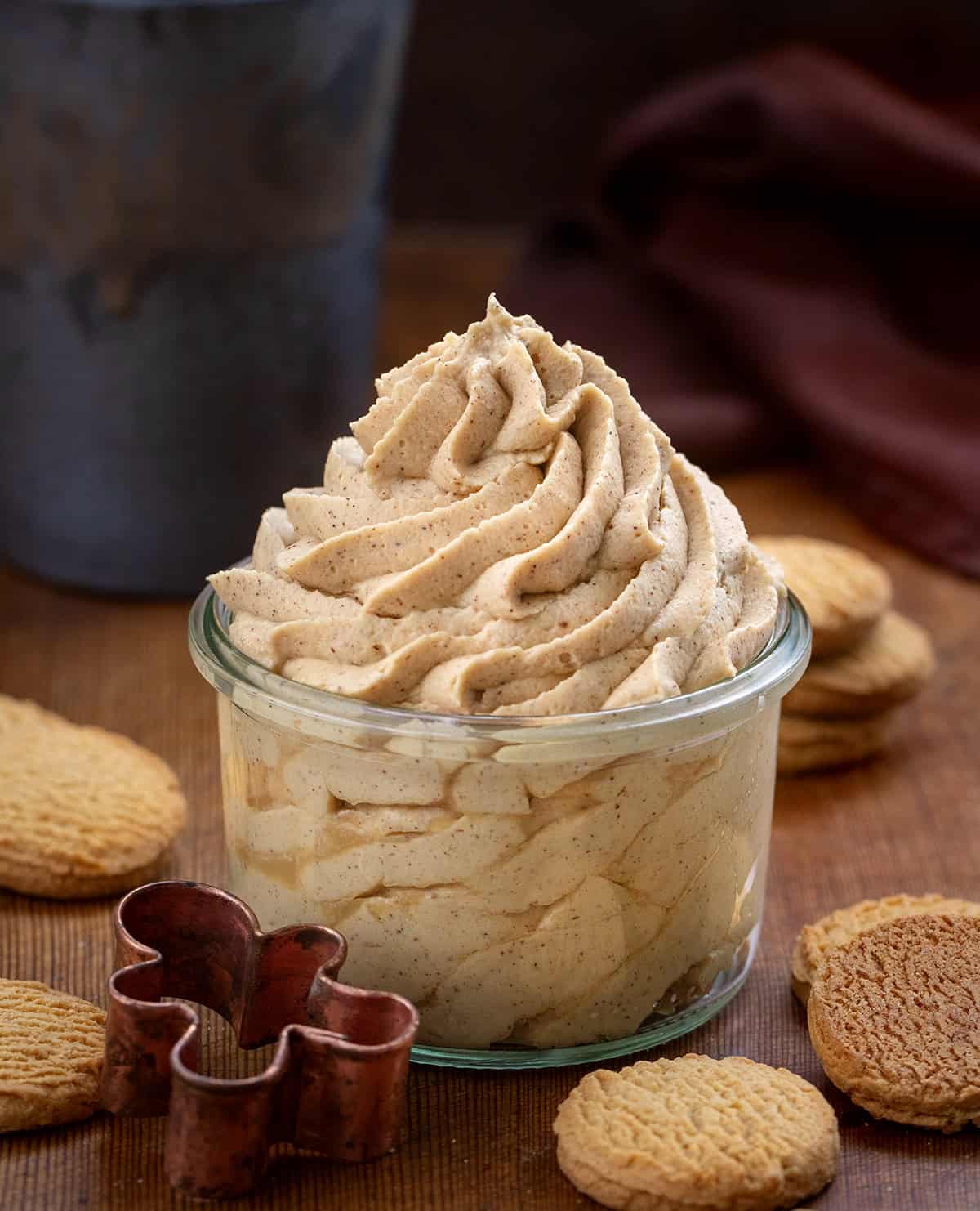 Gingerbread Stabilized Whipped Cream piped into a jar and on a wooden table with gingersnaps.