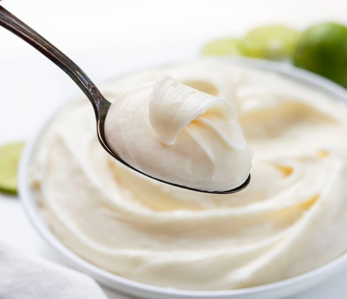 Spoonful of Key Lime Marshmallow Buttercream being held above the bowl.