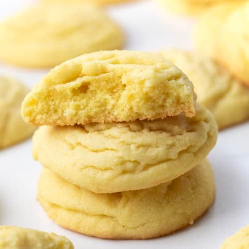 Small stack of Lemon Sugar Cookies with the top cookie broken in half showing delicate texture.