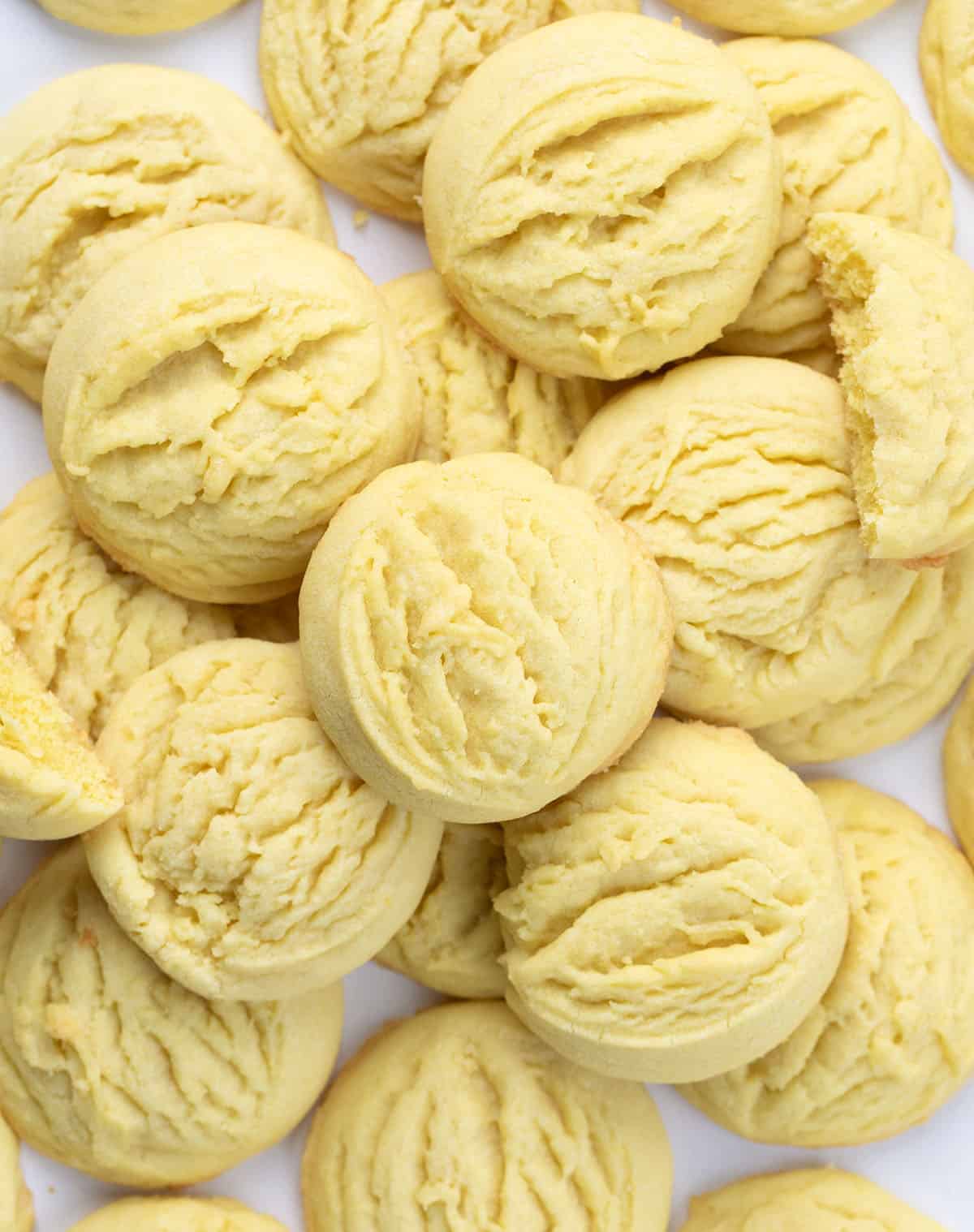 Lemon Sugar Cookies on a white table stacked with a couple of broken cookies from overhead Lemon Sugar Cookies on a white table stacked with a couple of broken cookies from overhead.