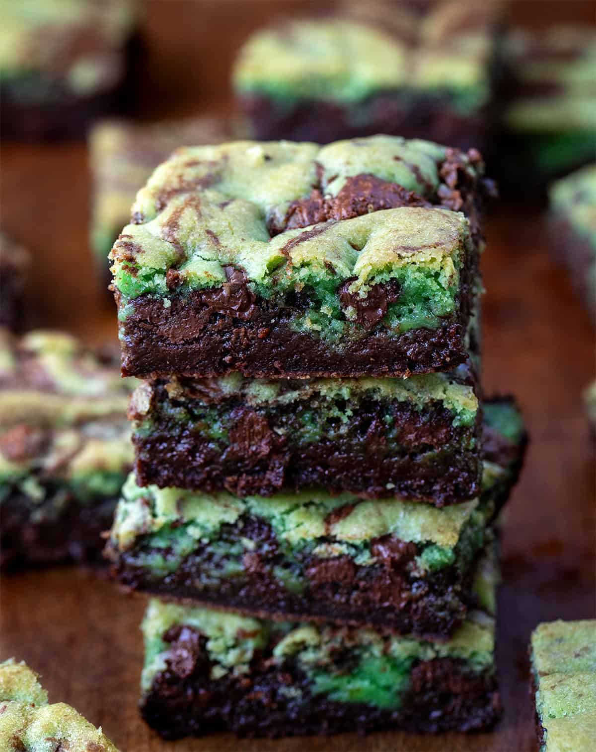 Stack of Mint Chocolate Chip Brookies on a wooden table surrounded by more brookies.