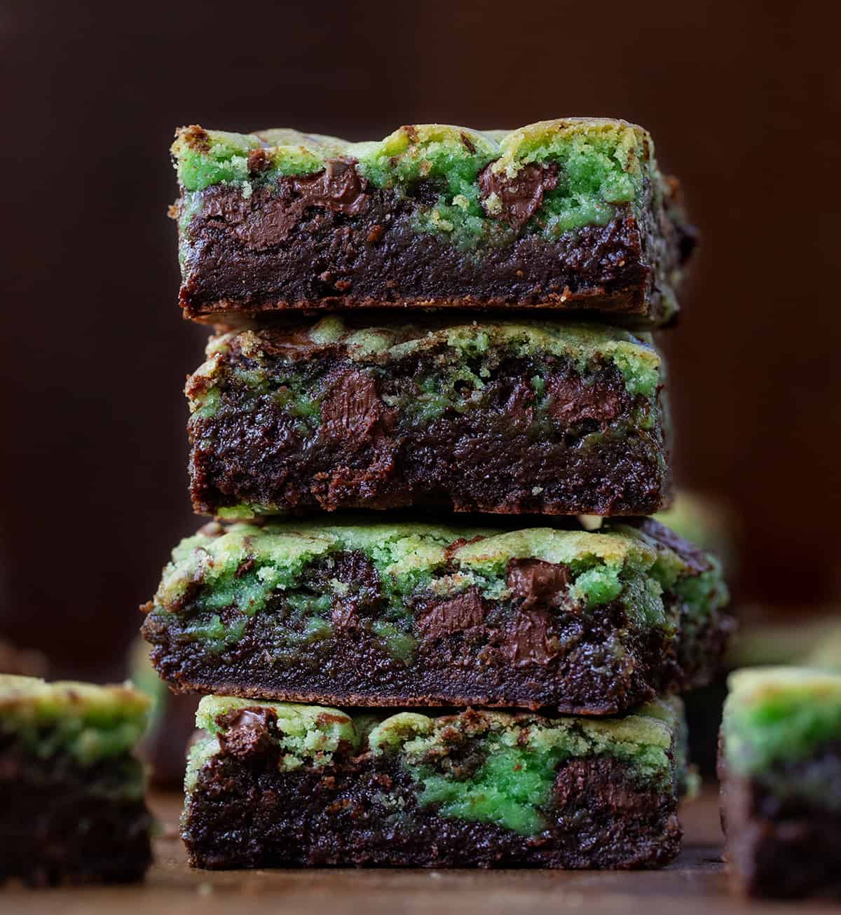 Close up of a stack of Mint Chocolate Chip Brookies on a wooden table.