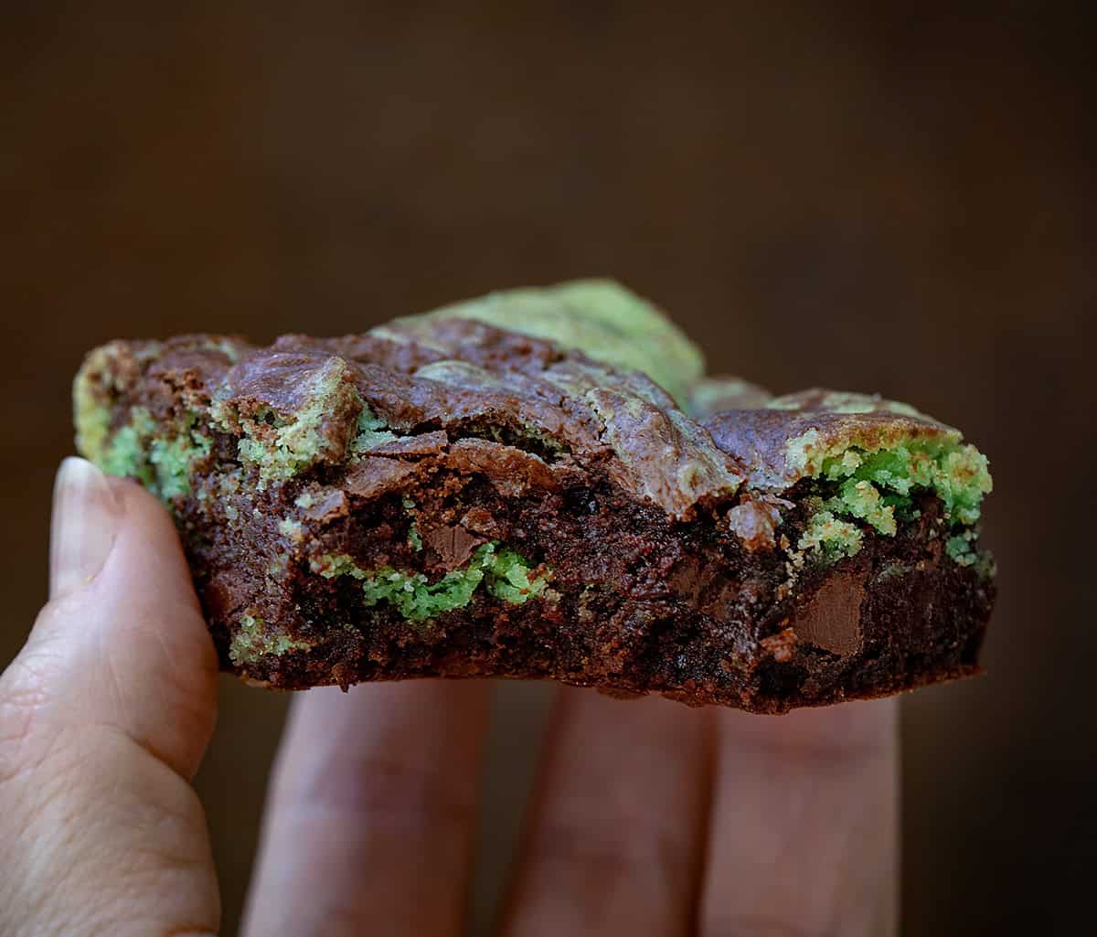 Hand holding a bit into Mint Chocolate Chip Brookie.