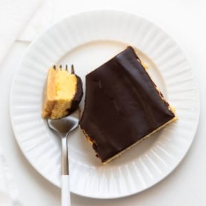 No Bake Boston Cream Pie Bar on a white plate with a small portion on a fork from overhead.