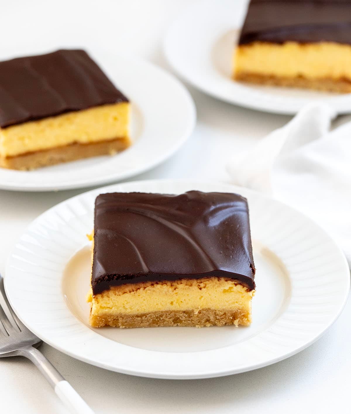 No Bake Boston Cream Pie Bars on white plates on a white table.