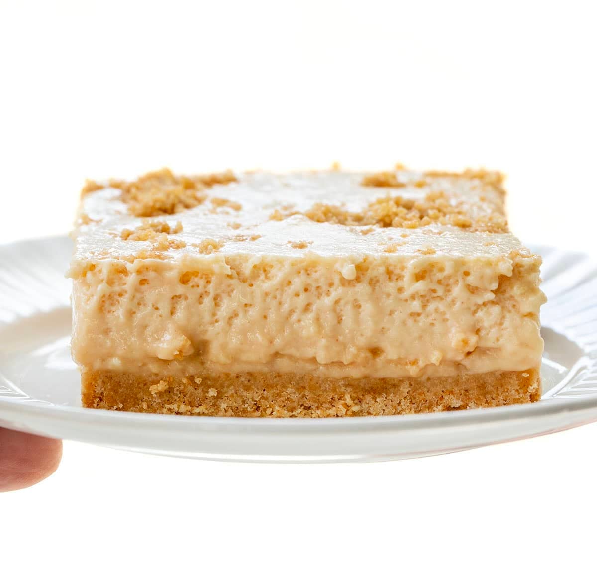 Hand holding a white plate with Peanut Butter Icebox Cheesecake on it.
