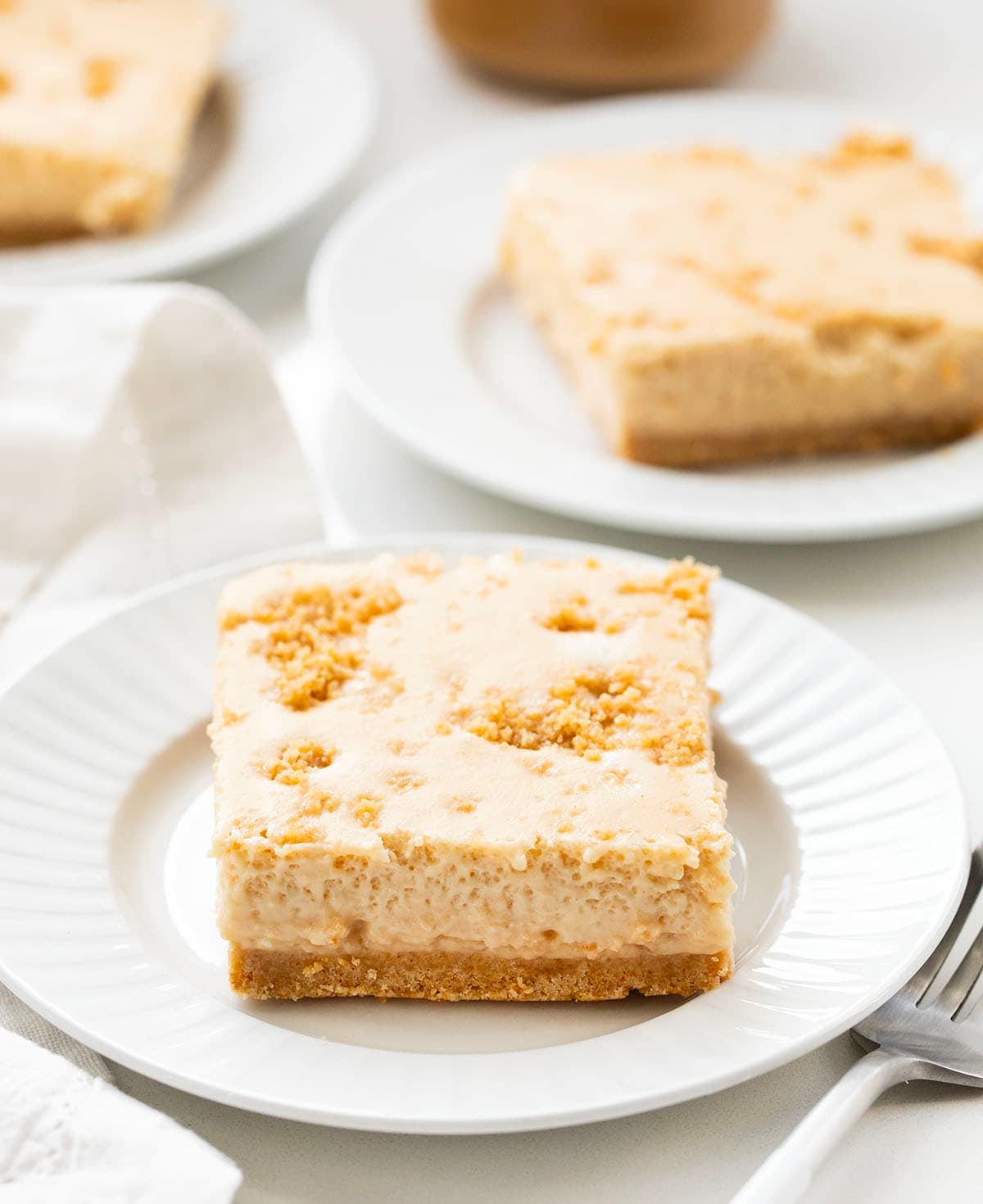 Peanut Butter Icebox Cheesecake pieces on white plates on a white table.