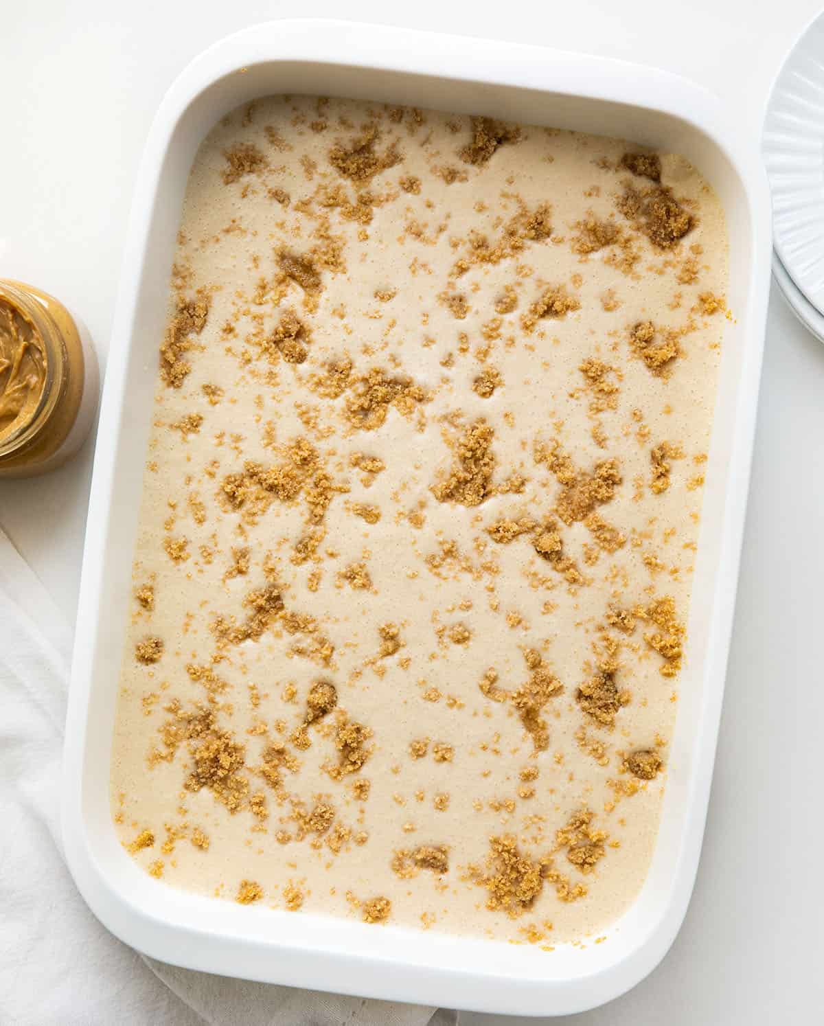 White pan with Peanut Butter Icebox Cheesecake in it on a white table with peanut butter from overhead.