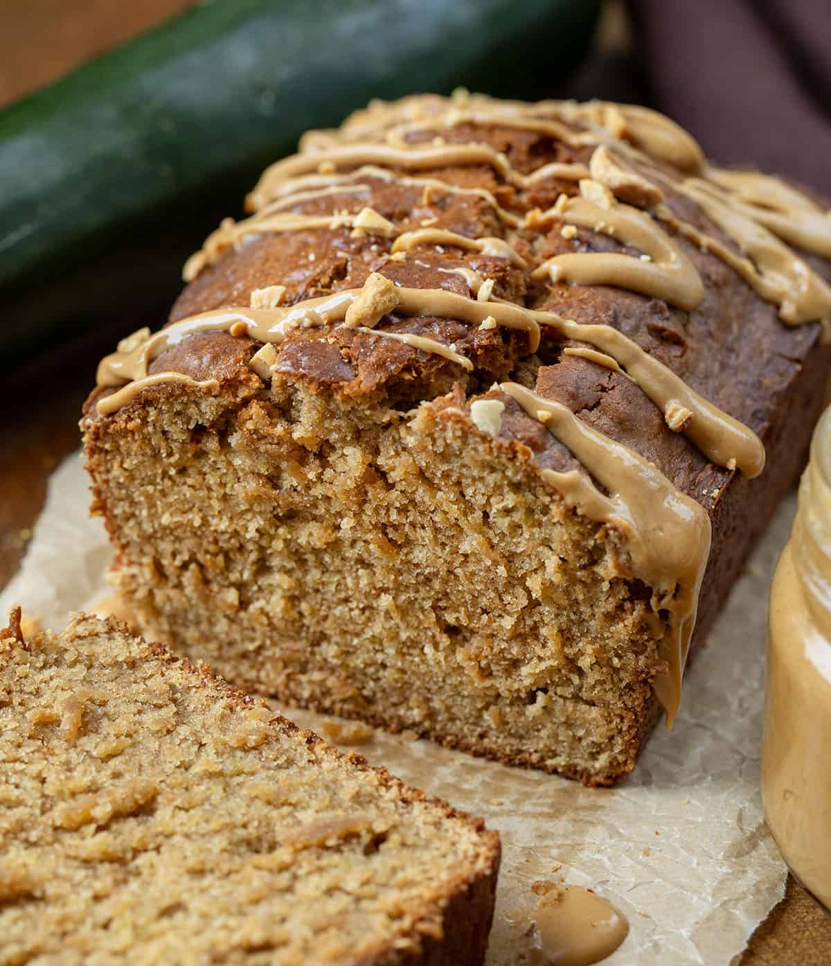 Close up of a cut into loaf of Peanut Butter Zucchini Bread near zucchini and peanut butter.