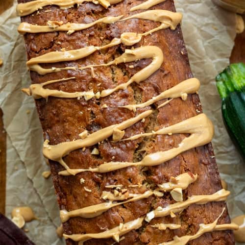 Close up of a loaf of Peanut Butter Zucchini Bread with zucchini and peanuts.