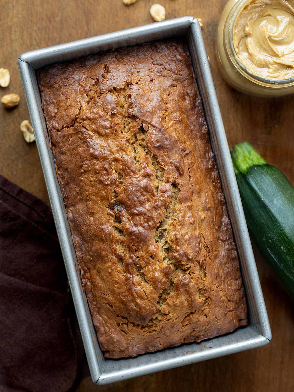 Close up of a loaf of Peanut Butter Zucchini Bread with zucchini and peanuts.