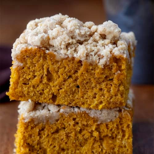 Two pieces of Pumpkin Streusel Sheet Cake stacked on a wooden table.