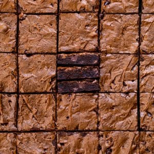 Sheet Pan Brownies cut into small squares with the center brownies on their side showing the tender texture.