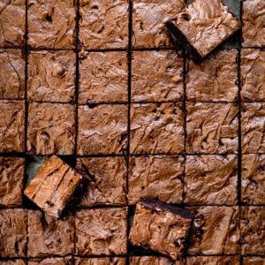 Chocolate Sheet Pan Brownies cut into small squares with some brownies at an angle.