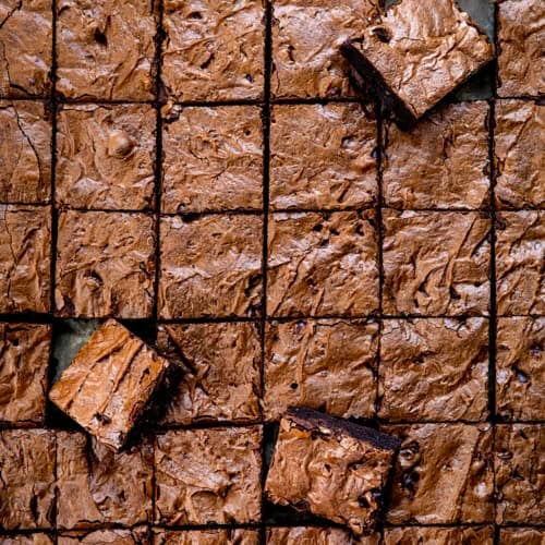 Chocolate Sheet Pan Brownies cut into small squares with some brownies at an angle.