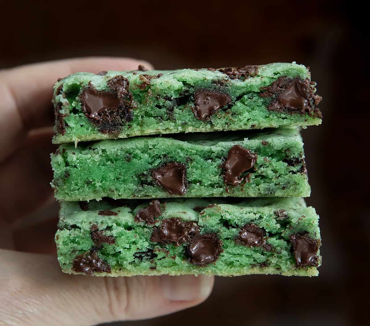 Hand holding three Sheet Pan Mint Chocolate Chip Cookies very close up.