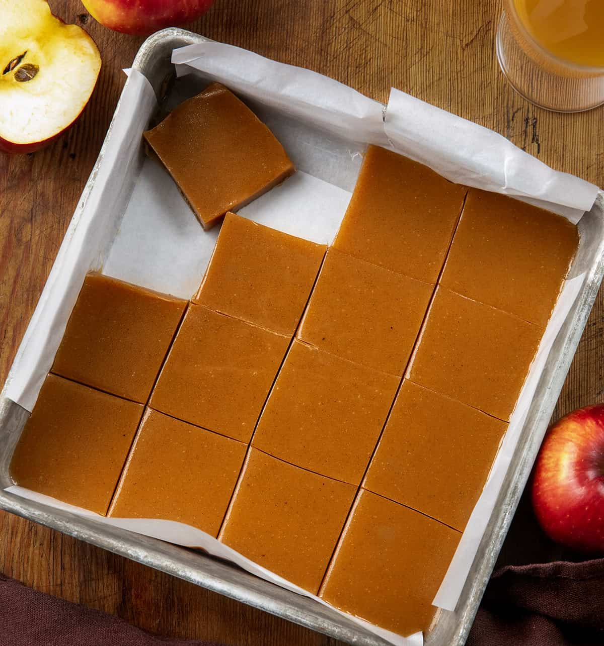 Pan of Apple Cider Caramels cut into squares on a wooden table from overhead.