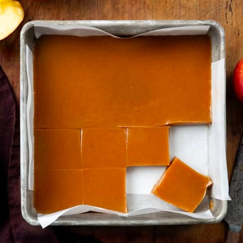 Pan of Apple Cider Caramels with some cut into squares on a wooden table from overhead.