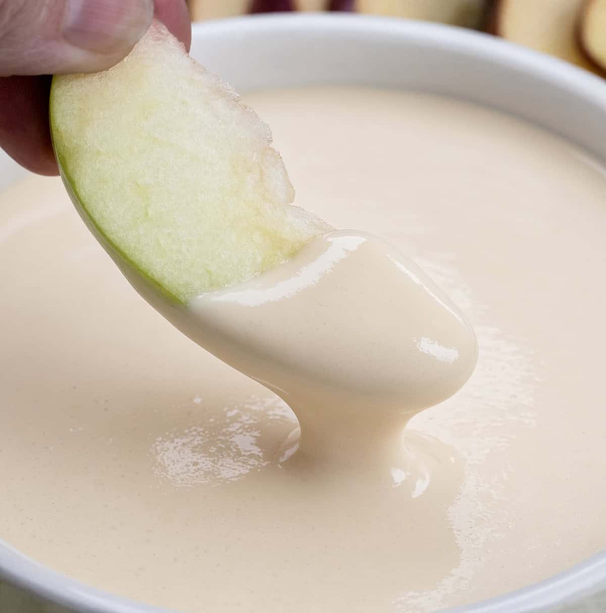 Dipping a slice of green apple into Apple Cider Marshmallow Sauce.