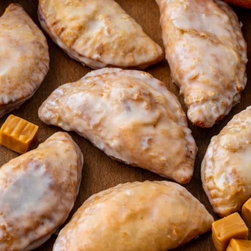 Caramel Apple Hand Pies laying flat on a wooden table from overhead.