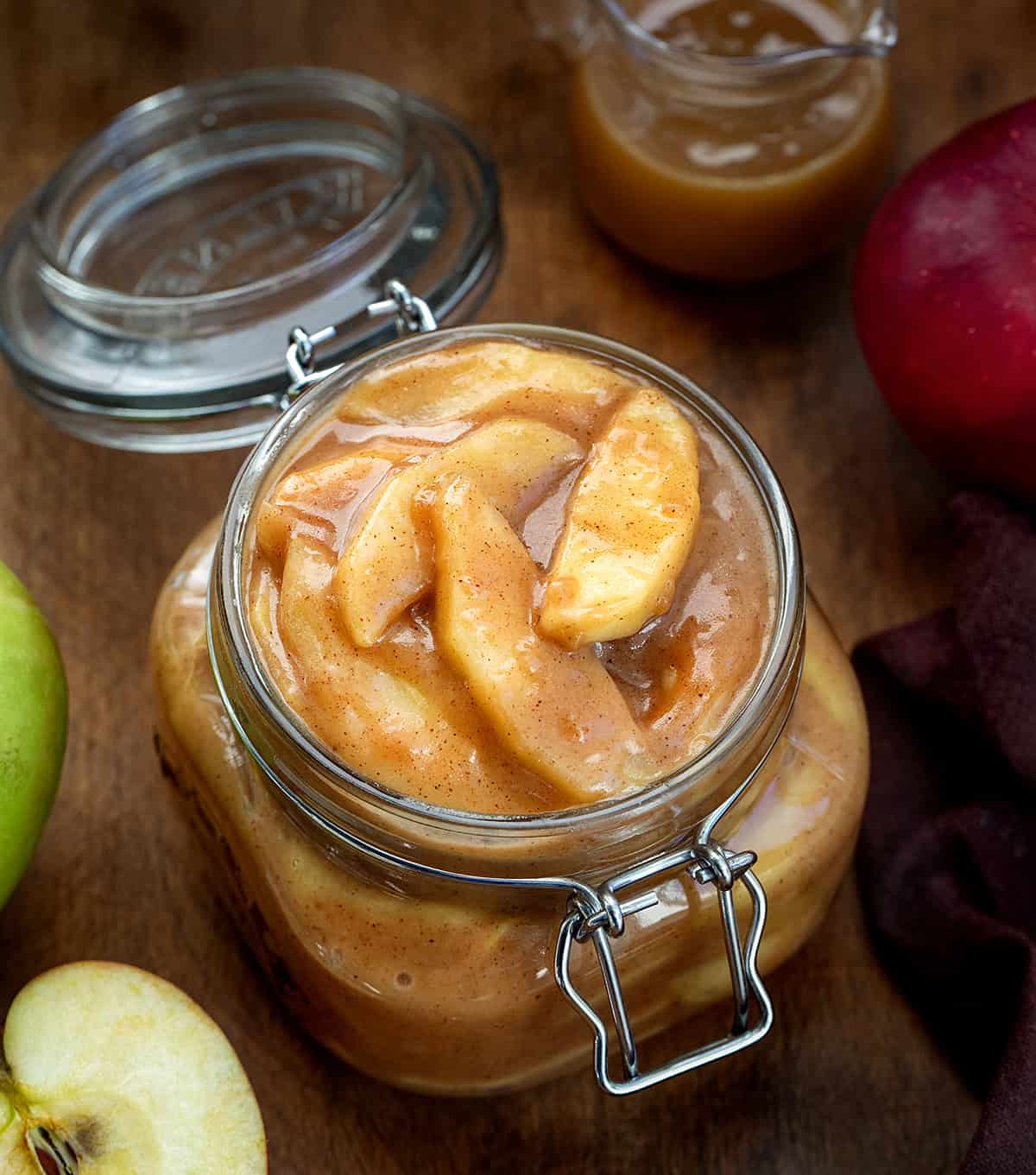 Jar of Caramel Apple Pie Filling on a wooden table with caramel and apples Jar of Caramel Apple Pie Filling on a wooden table with caramel and apples.