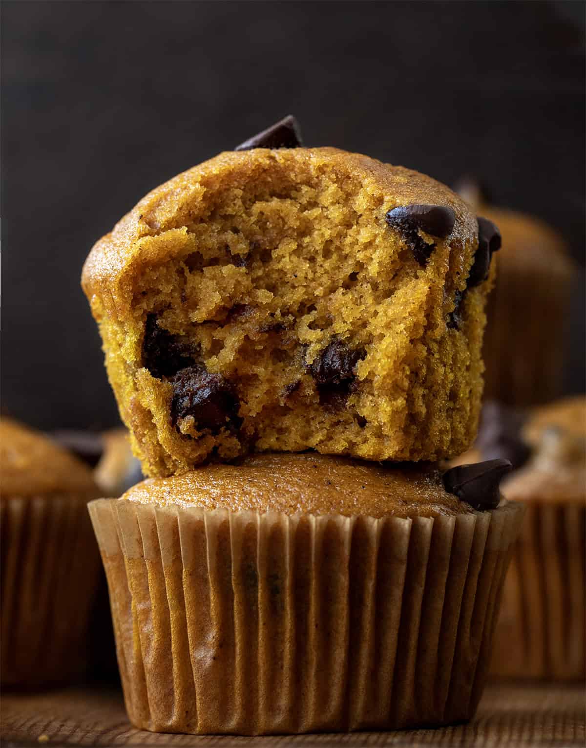 Stack of Chocolate Chip Pumpkin Muffins with the top muffin halved showing inside texture.