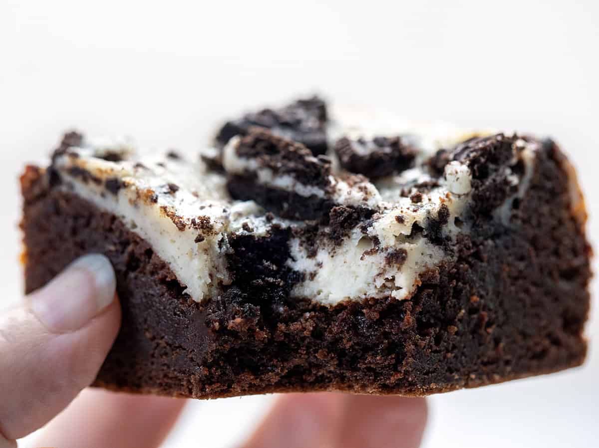 Hand holding a bit into Cookies and Cream Brownie.