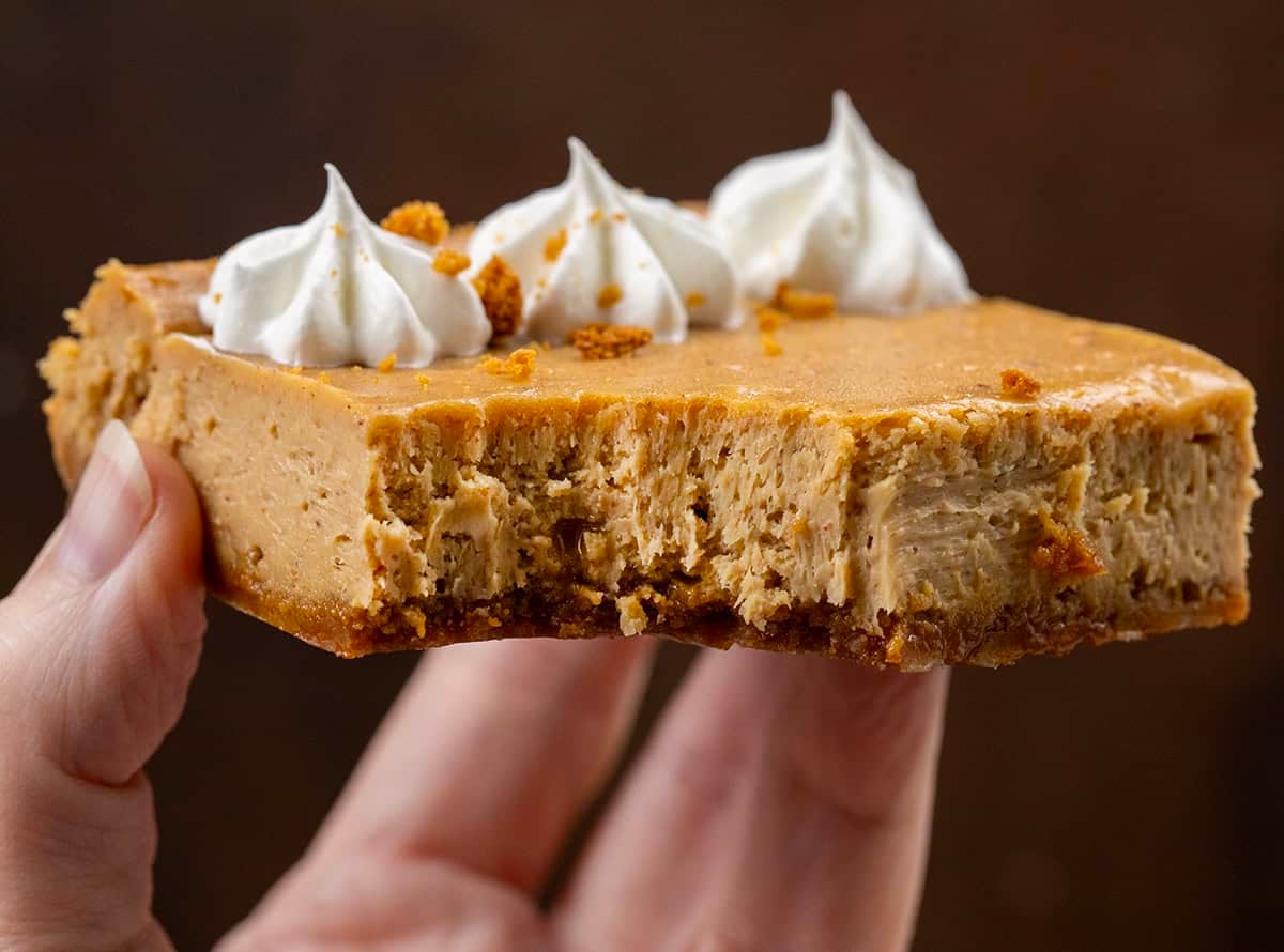 Hand holding a bit into Gingerbread Cheesecake Bar.