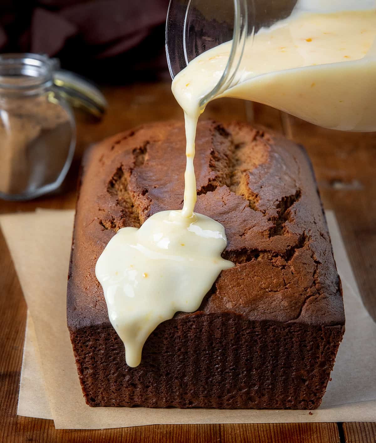 Pouring orange glaze over a gingerbread loaf.