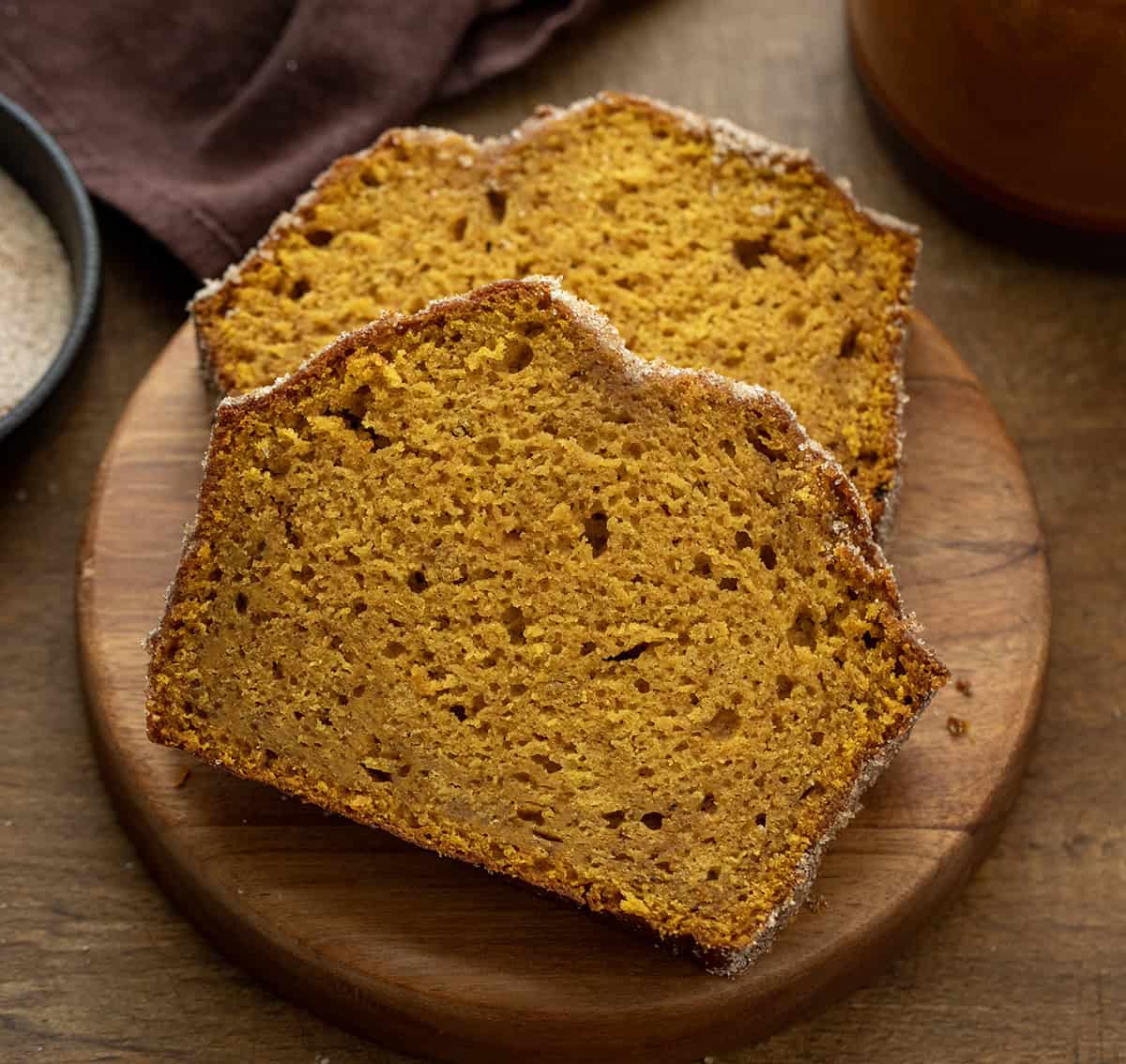 Slices of Pumpkin Donut Bread on a wooden plate on a wooden table.
