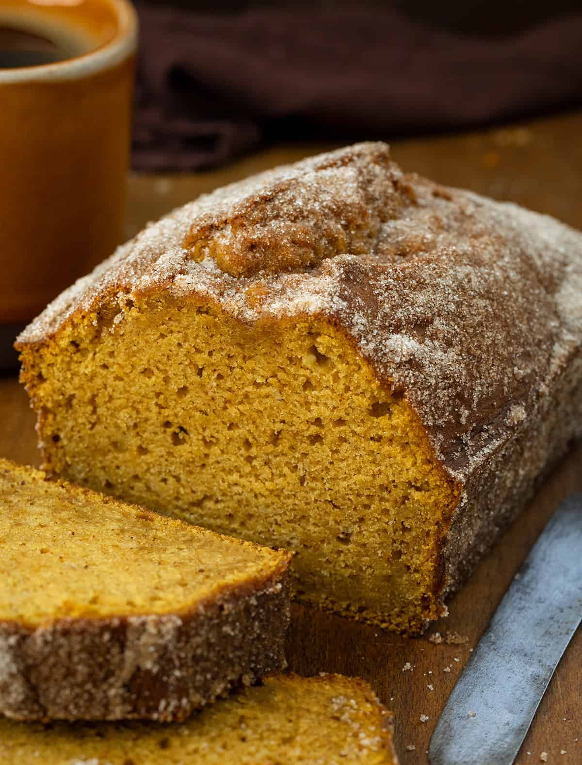Cut into loaf of Pumpkin Donut Bread with some pieces laying in front of the loaf.