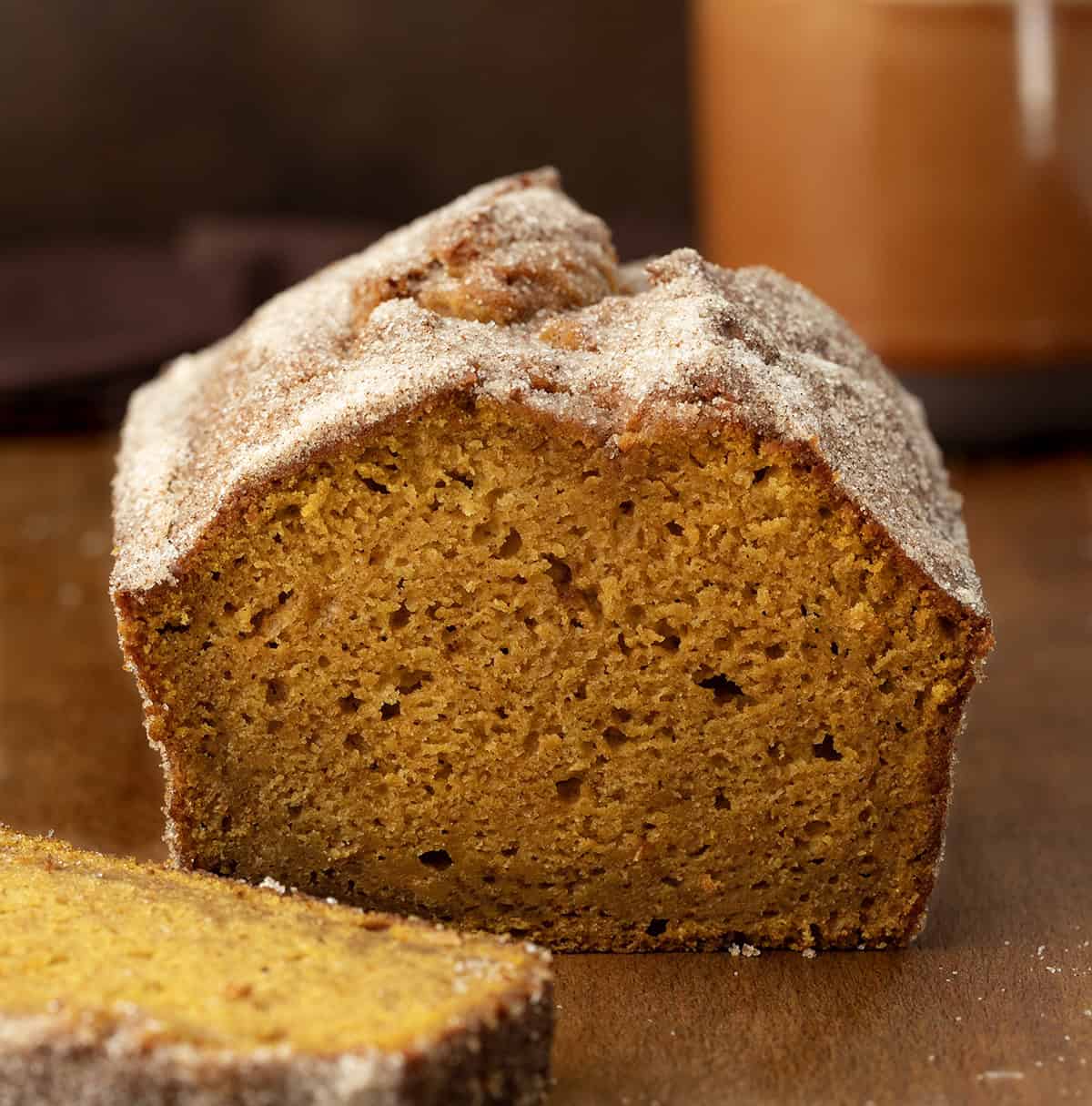 Cut into loaf of Pumpkin Donut Bread with one piece laying plate in front of it.