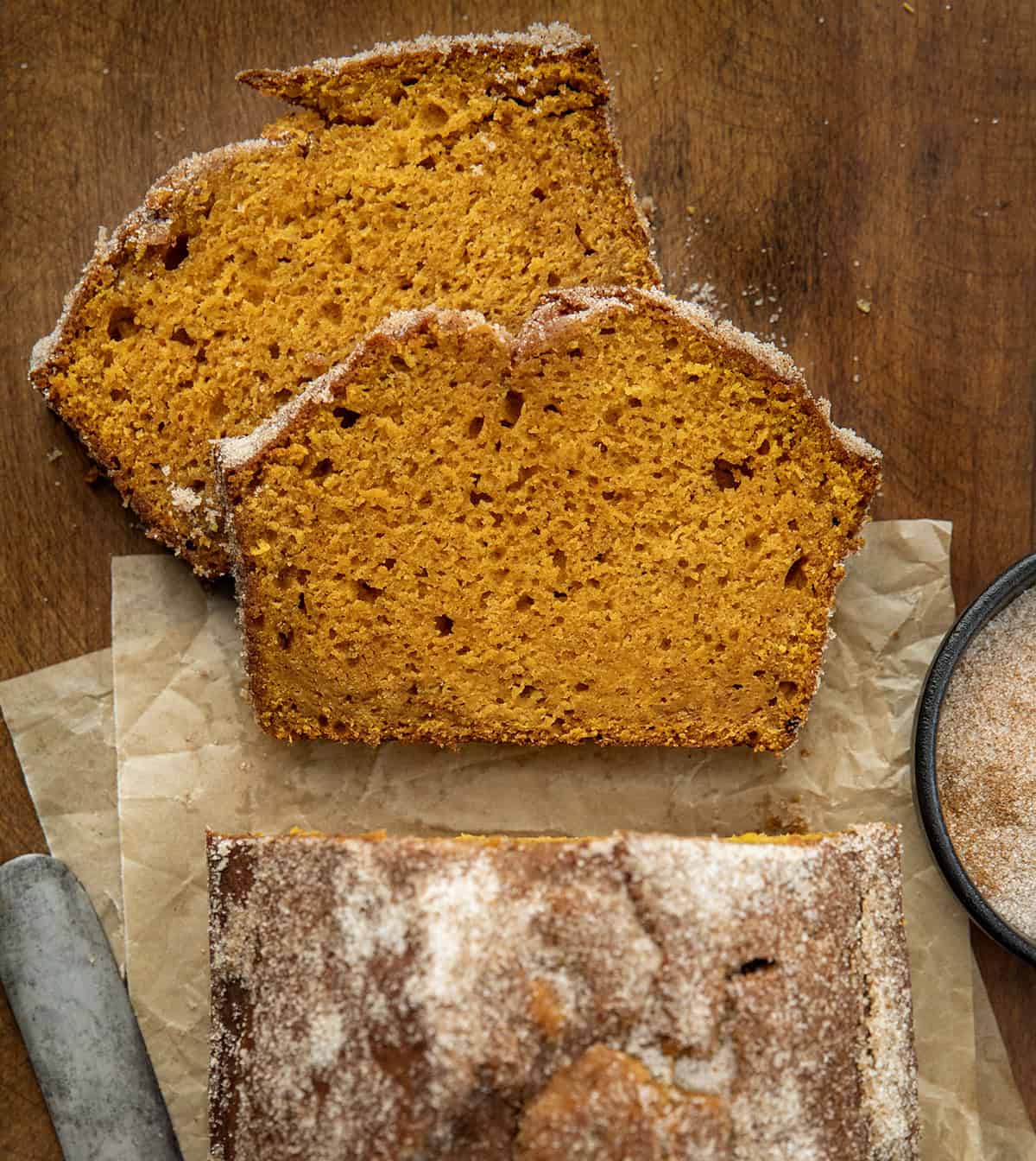 Pumpkin Donut Bread with some pieces cut and laying flat on a wooden table from overhead.