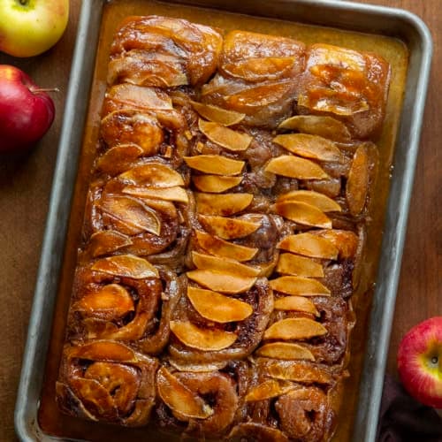 Apple Caramel Rolls on a sheet pan on a wooden table from overhead.