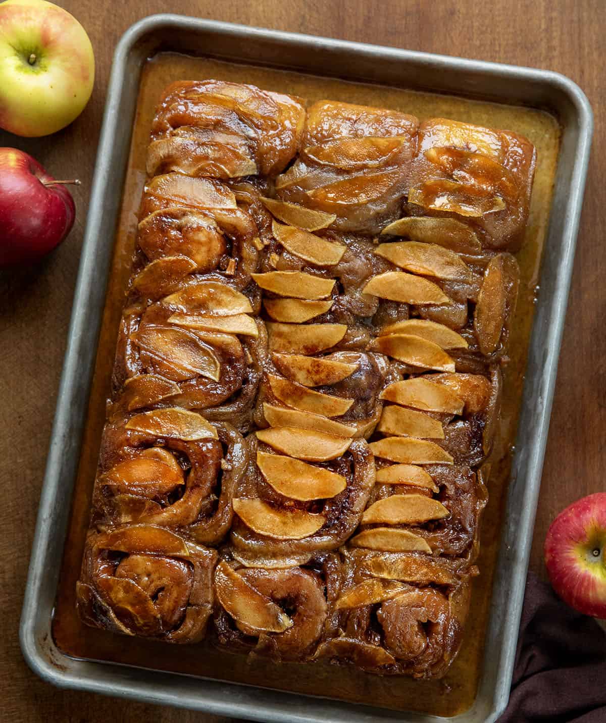 Apple Caramel Rolls on a sheet pan on a wooden table from overhead.