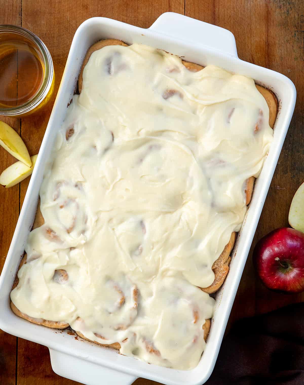 Apple Cider Cinnamon Rolls in the baking dish on a wooden table from overhead.