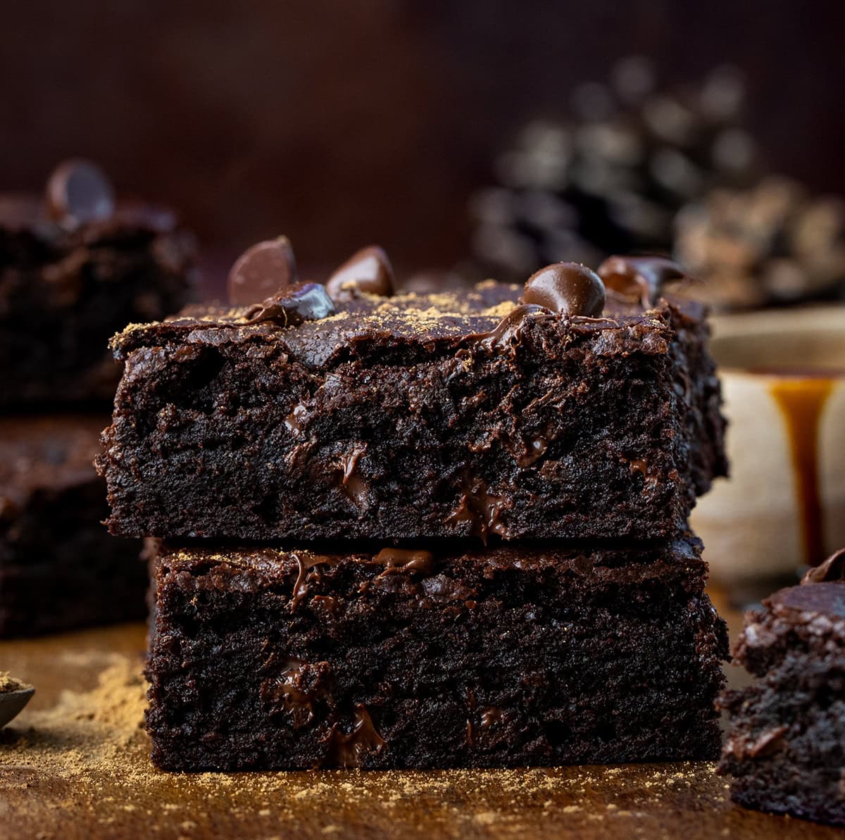Small stack of Chocolate Gingerbread Brownies on a wooden table with molasses and chocolate chips.