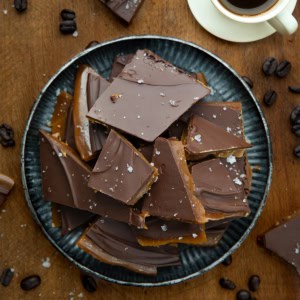 Platter of Coffee Toffee on a wooden table with a cup of coffee from overhead.