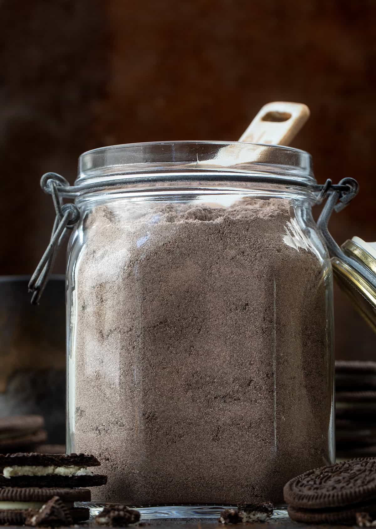 Big jar of Cookies & Cream Hot Cocoa Mix with a measuring spoon in it.