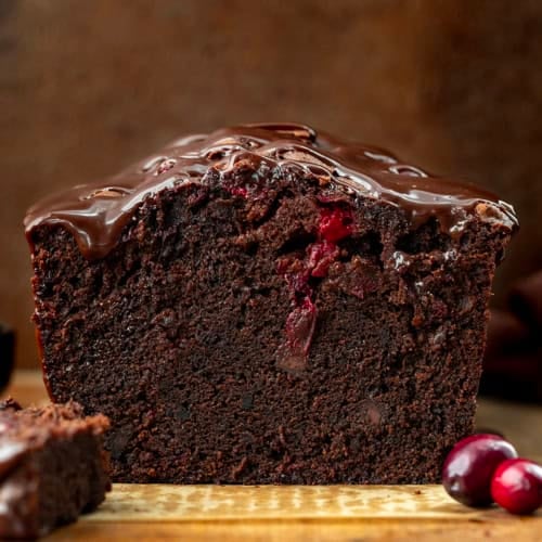 Looking straight on at a loaf of Cranberry Brownie Bread that has been cut into showing the inside texture.