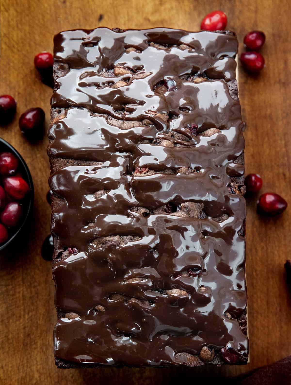 Whole loaf of Cranberry Brownie Bread on a wooden table from overhead.
