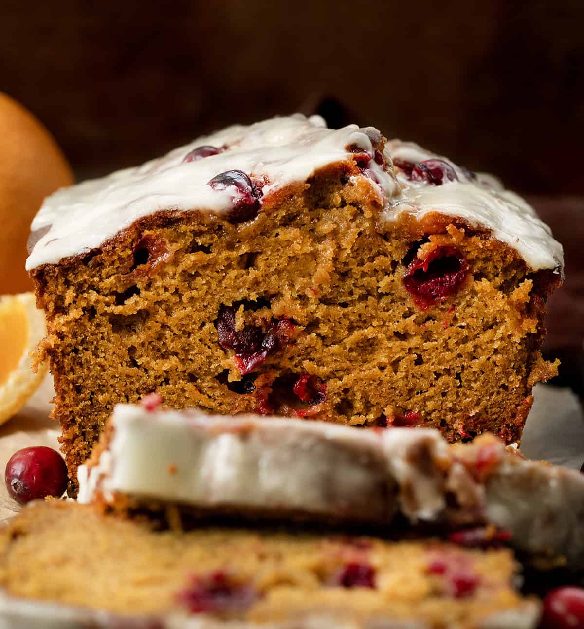 Close up of a loaf of Cranberry Orange Pumpkin Bread that has a few slices cut and laying flat Close up of a loaf of Cranberry Orange Pumpkin Bread that has a few slices cut and laying flat.