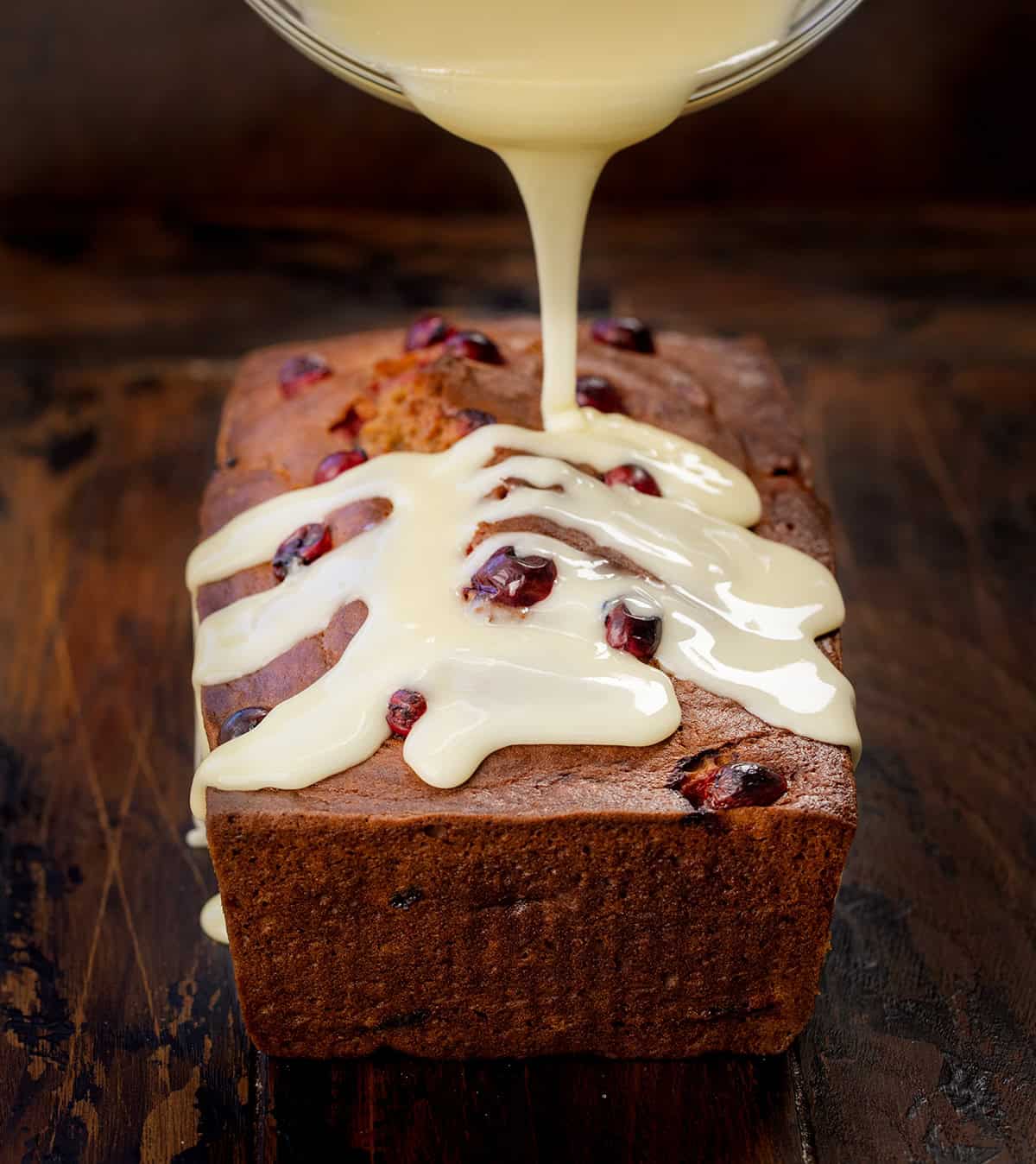Drizzling orange glaze over a loaf of cranberry pumpkin bread Drizzling orange glaze over a loaf of cranberry pumpkin bread.