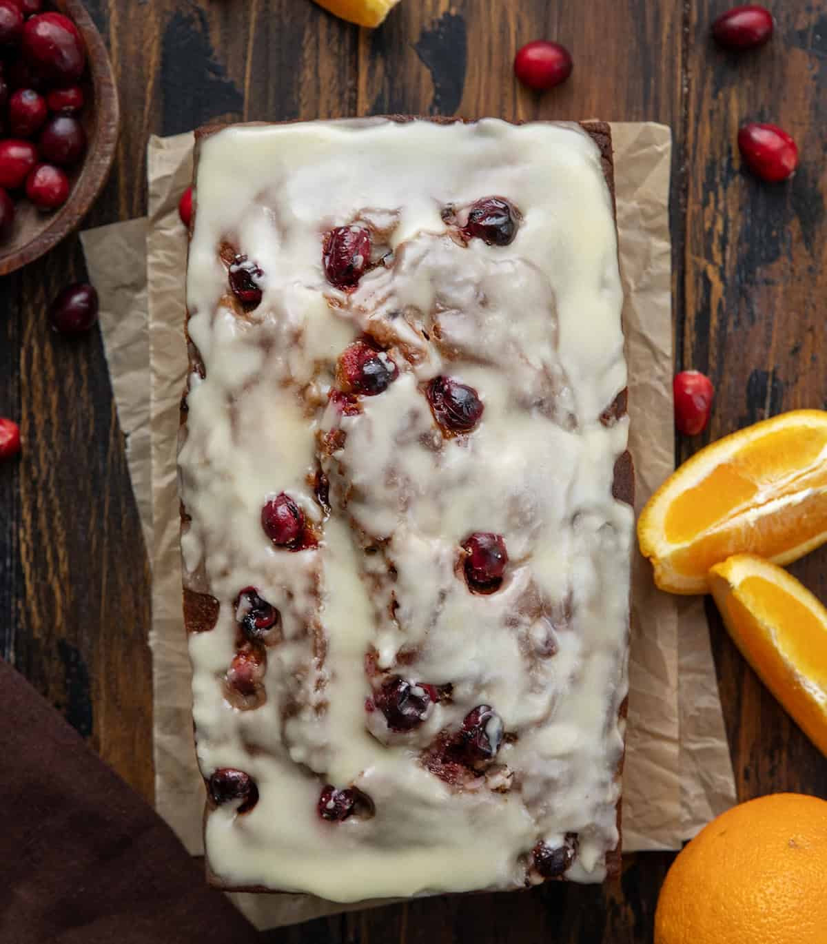 Loaf of Cranberry Orange Pumpkin Bread on a wooden table with fresh cranberries and oranges from overhead Loaf of Cranberry Orange Pumpkin Bread on a wooden table with fresh cranberries and oranges from overhead.