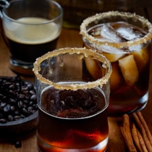 Glasses of Maple Bourbon Espresso and an espresso on a wooden table with coffee beans.